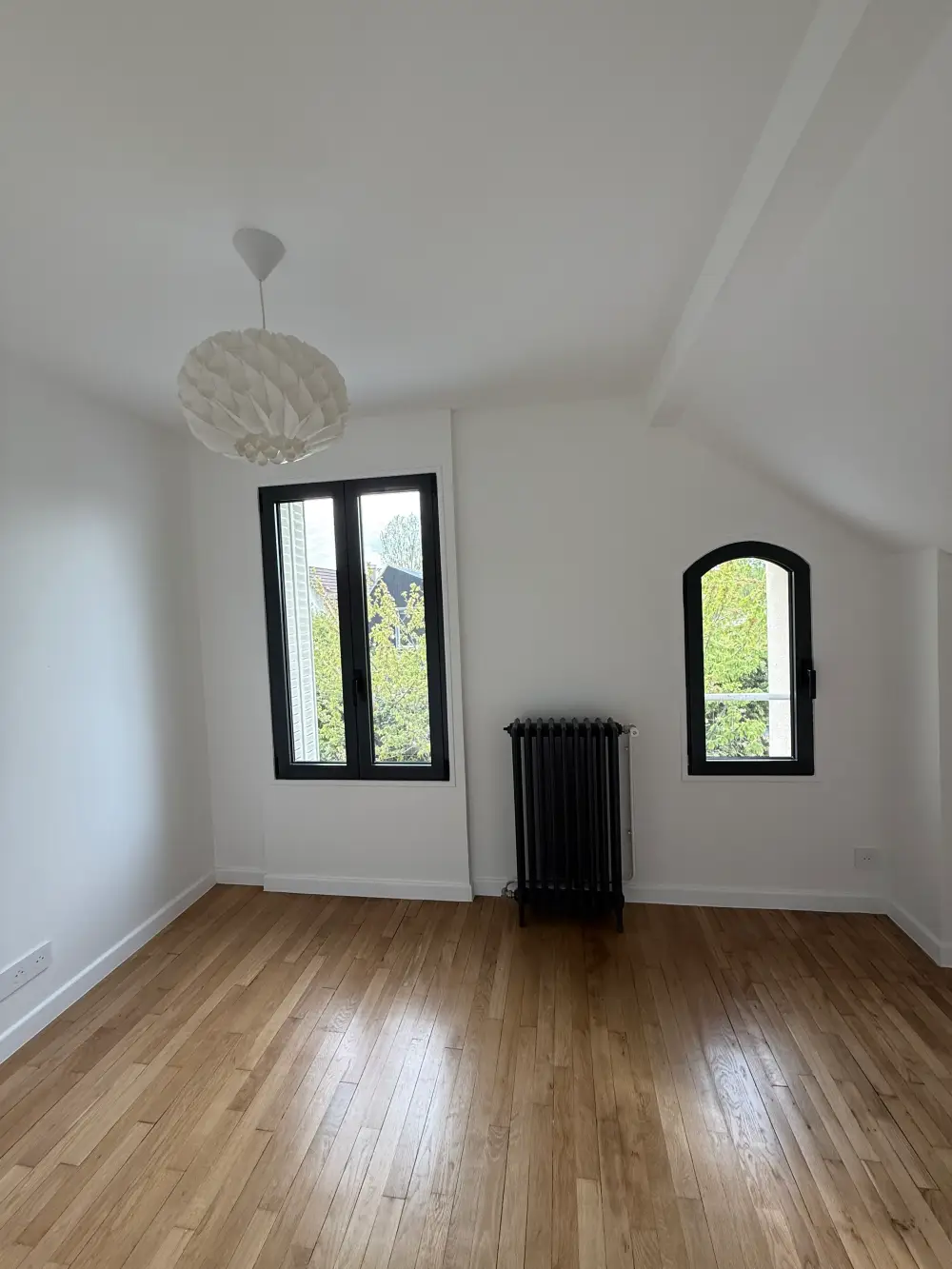 Chambre rénovée avec parquet et fenêtres noires dans une maison à Clamart