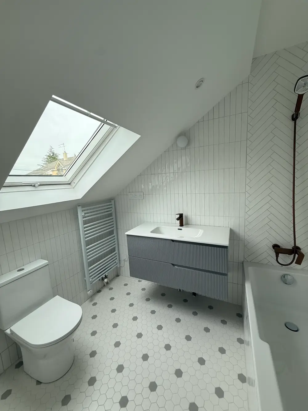Salle de bain sous combles rénovée avec baignoire et fenêtre de toit à Clamart