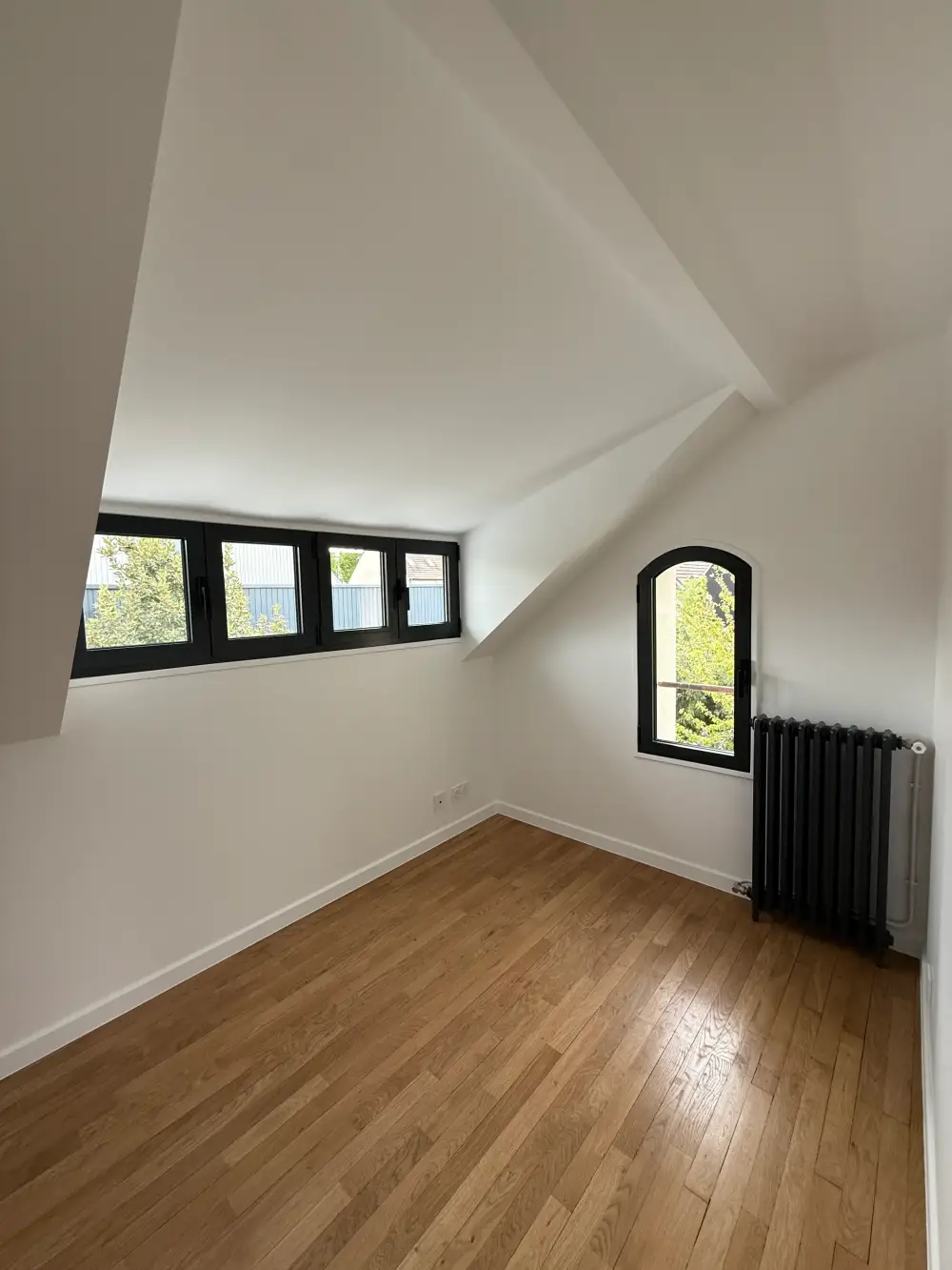 Chambre sous combles rénovée avec parquet et radiateur noir à Clamart