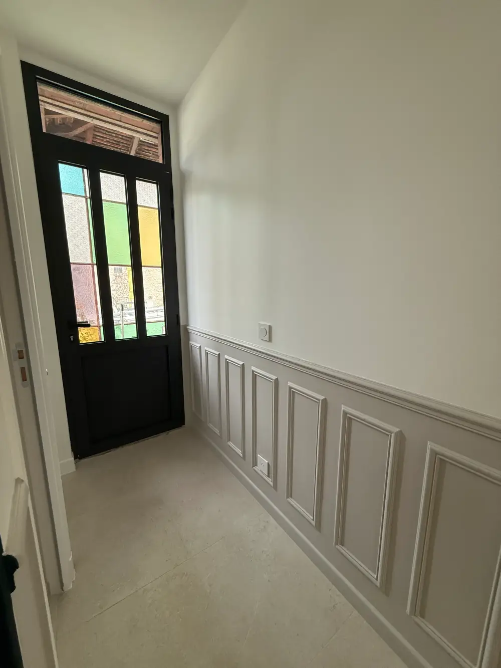 Entrée rénovée avec soubassement mouluré et porte noire à Clamart