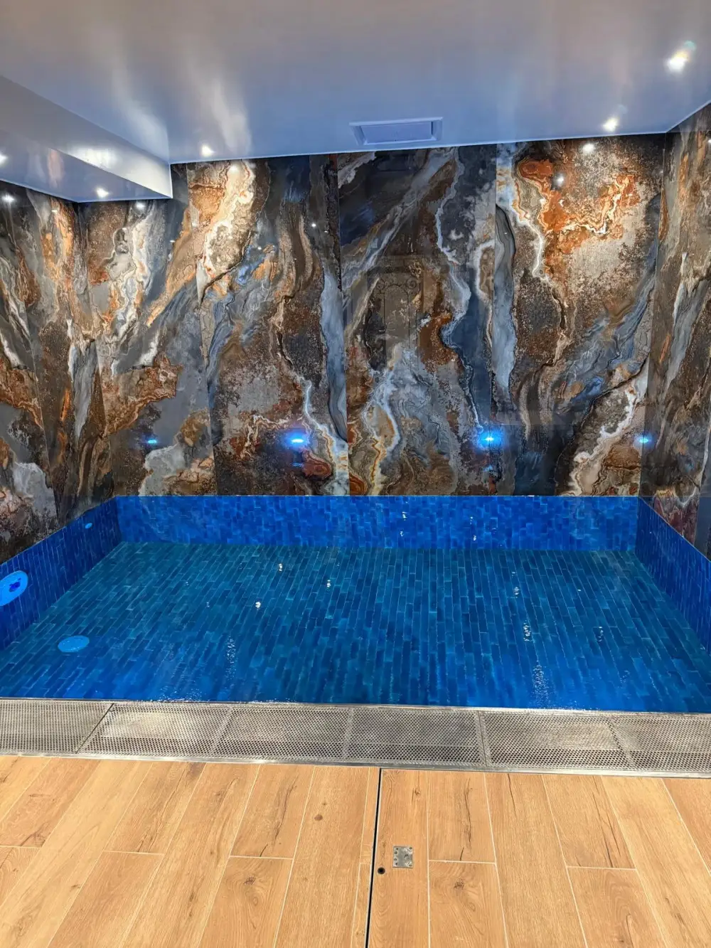Bassin intérieur rénové avec revêtement bleu et carrelage mural effet pierre