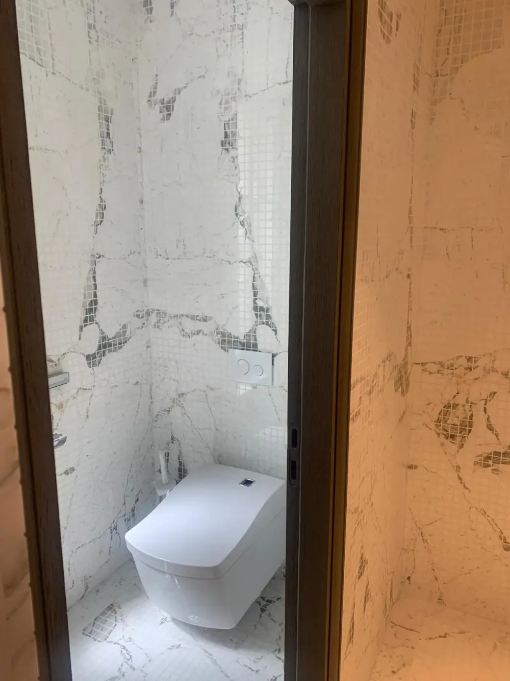 WC suspendu avec mosaïque effet marbre dans une salle de bain rénovée