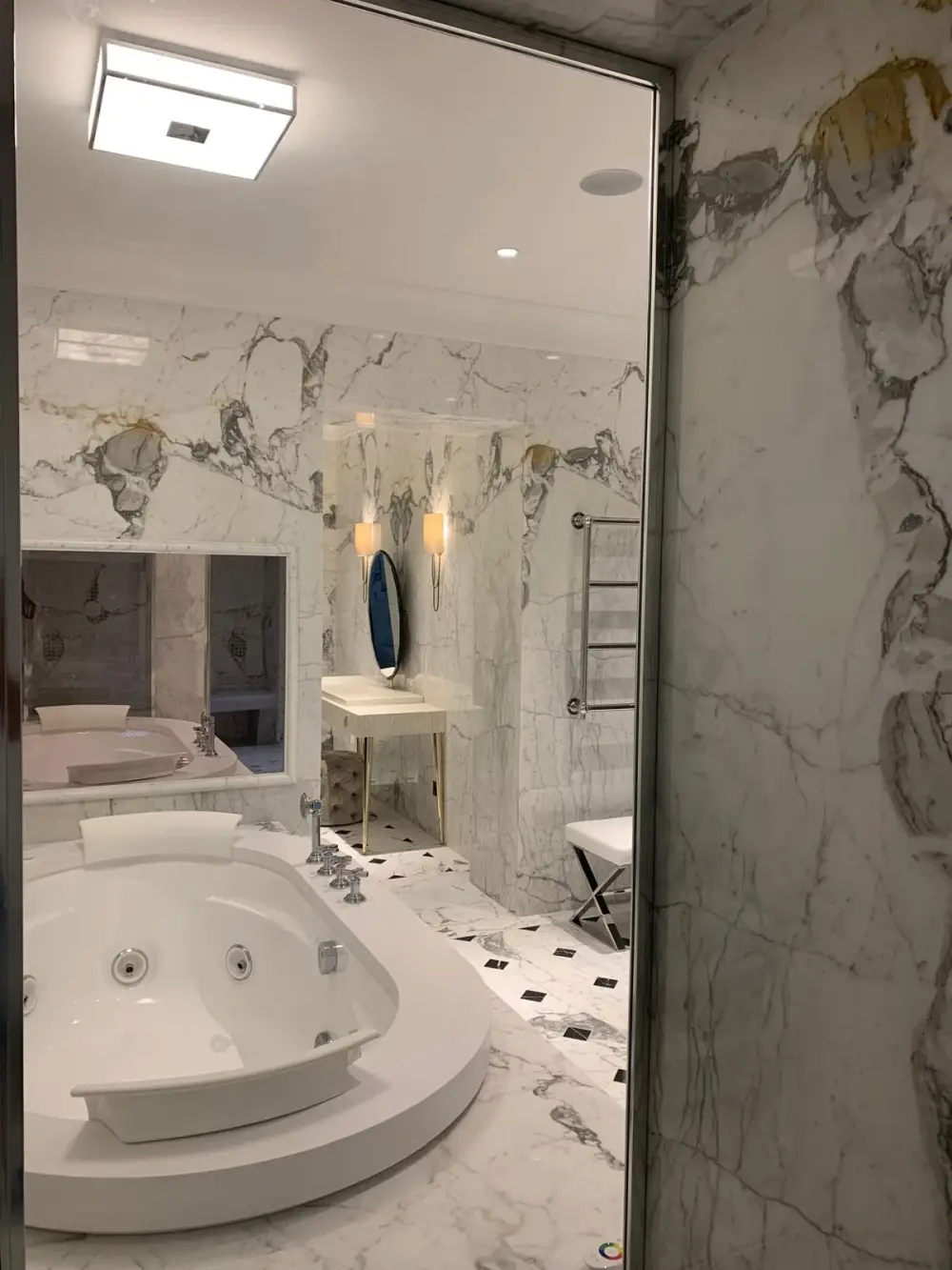 Salle de bain en marbre avec baignoire balnéo et porte vitrée dorée